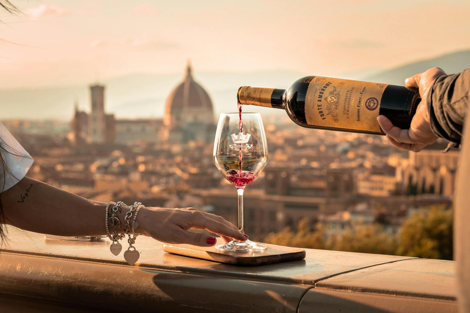 Imagen de una copa de vino sirviendo en un vaso con paisaje de fondo de Florencia.